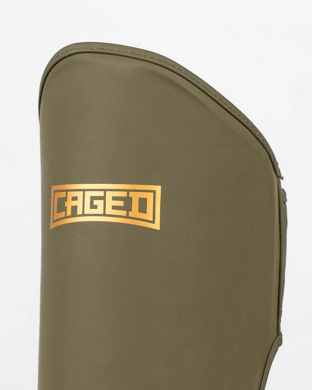 Espinilleras Caged Shadow – Caqui/Oro